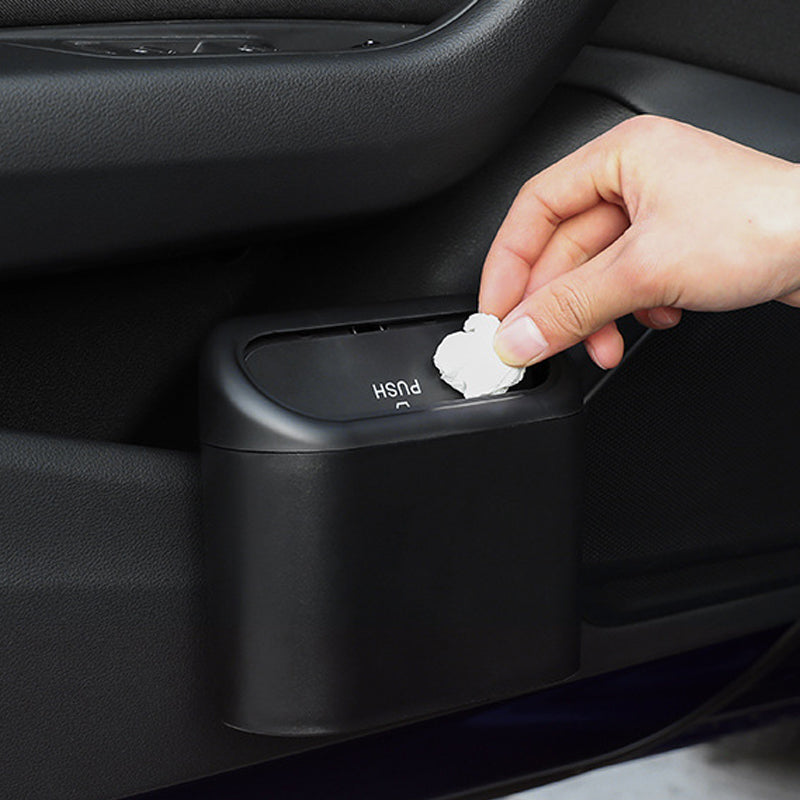 Mão inserindo papel no caixote do lixo portátil para carro na porta do veículo