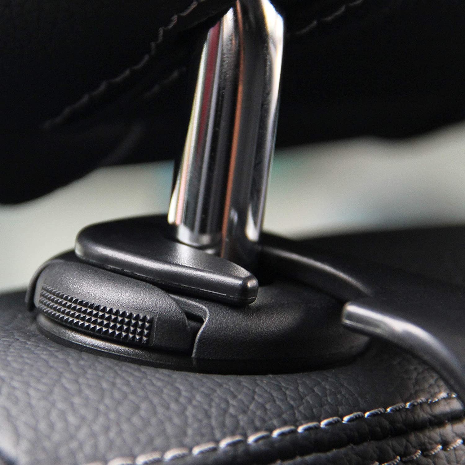 Detalhe de um gancho resistente preto preso ao apoio de cabeça do assento do carro, destacando sua compatibilidade e facilidade de instalação
