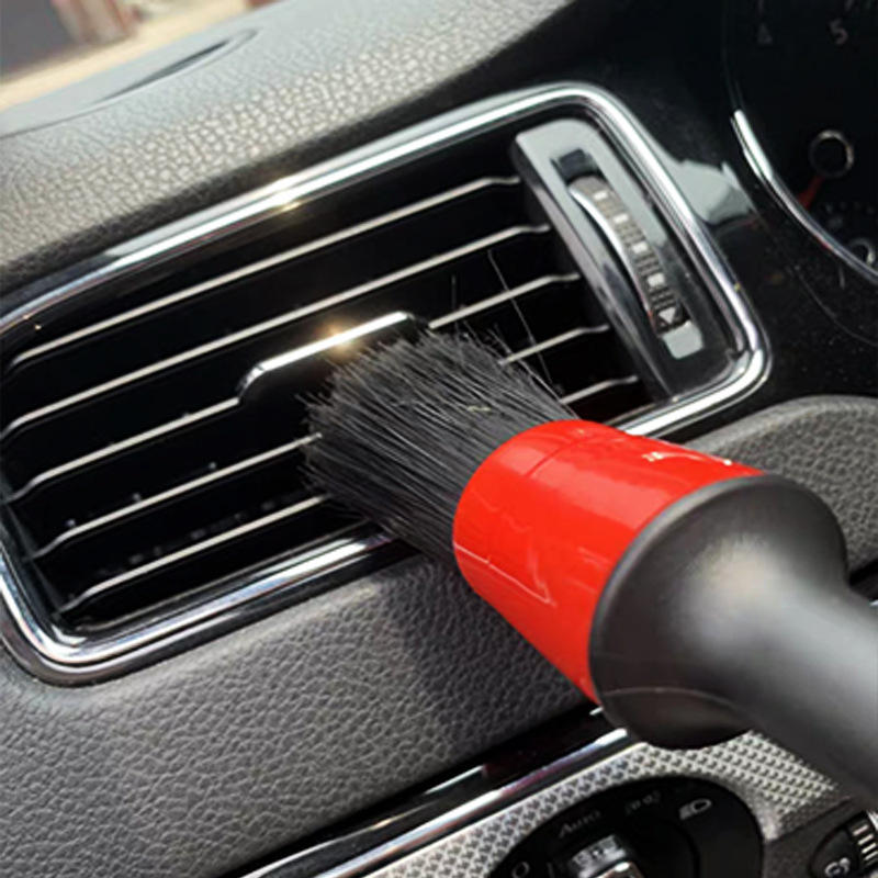 Escova de detalhe com cabo preto e vermelho usada em ventilação de carro para limpeza interna automóvel