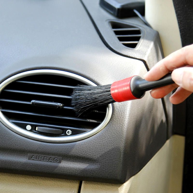 Escova de detalhe em uso, mostrando eficácia na limpeza nas saídas de ar do veículo automóvel